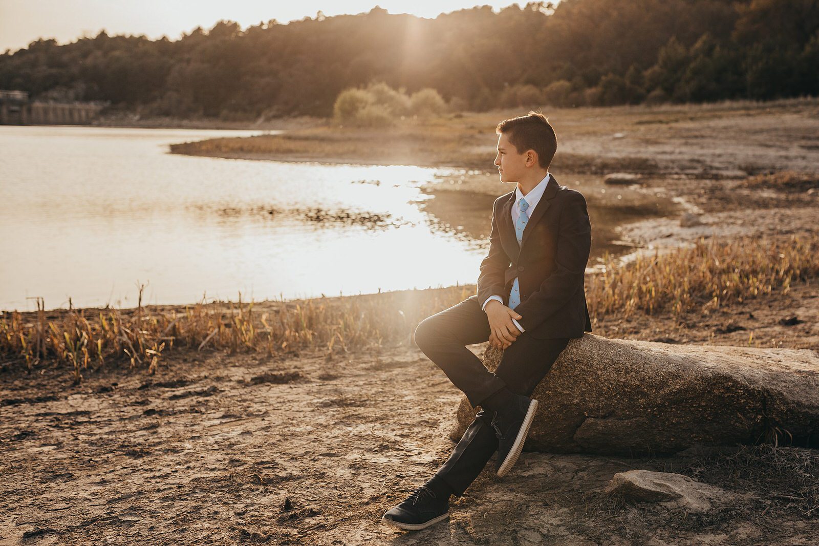 Sesiones fotograficas de comunion en la naturaleza con un niño mirando el atardecer.